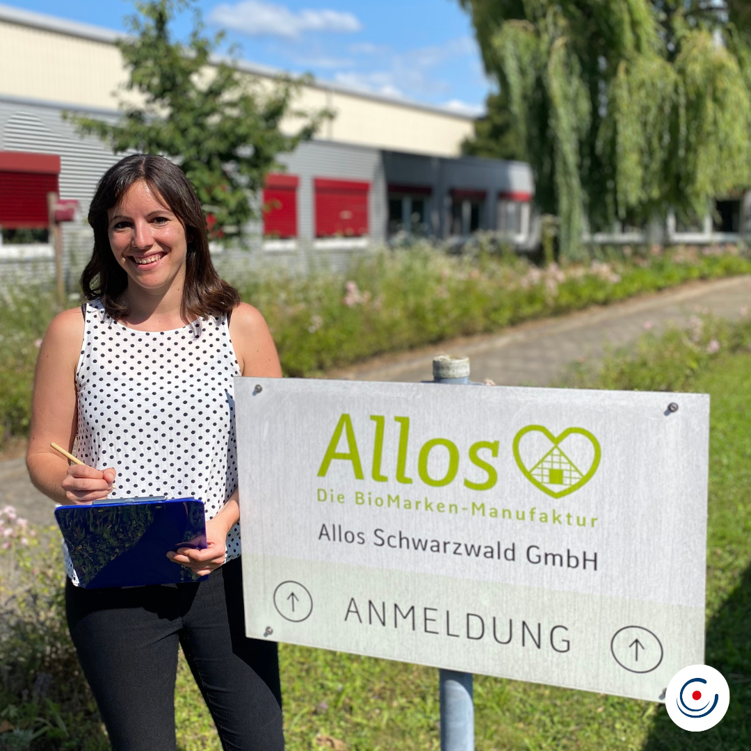 Unsere Kollegin und Projektverantwortliche KEEN Catrina Heider vor dem Allos-Firmen-Schild