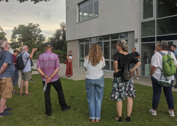 Eine Gruppe von Menschen auf einer Grünfläche vor einem Gebäude beim Hitzespaziergang in Ettenheim.